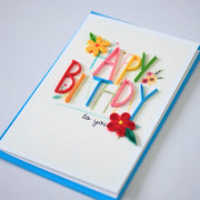 Side view showing multicolored paper lettering and small red and yellow flowers