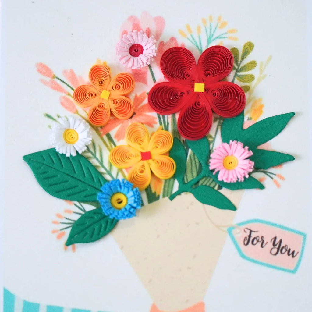 Detail of raised multicolored paper flowers and green leaves in a bouquet