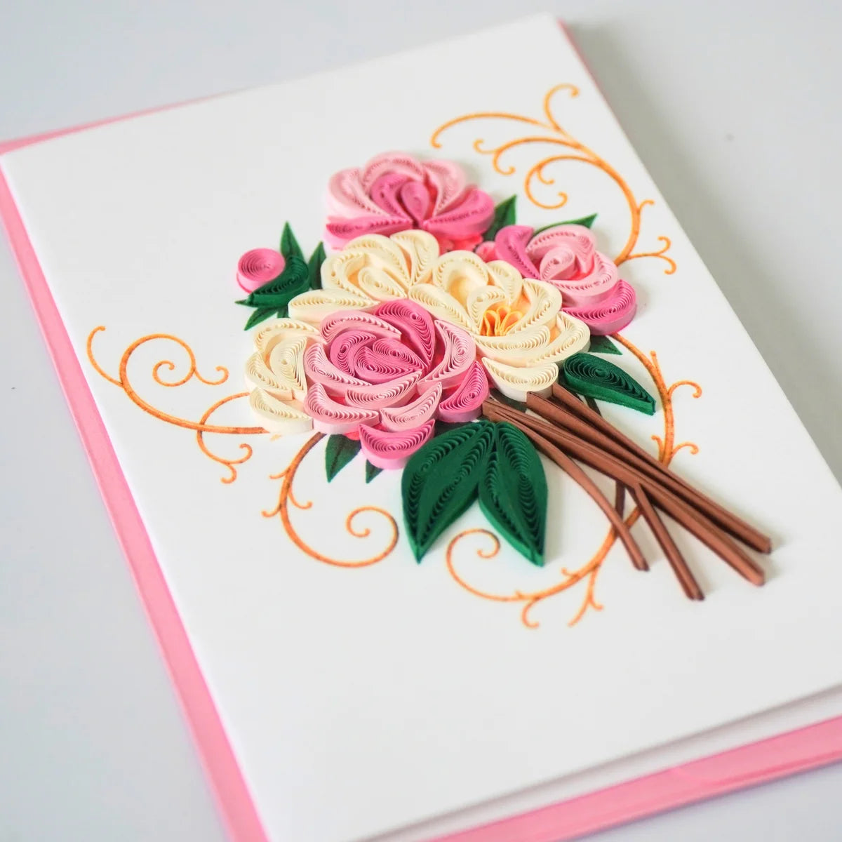 Angled view of pink and ivory rose bouquet quilled greeting card with green paper leaves