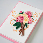 Side view showing coiled pink and ivory paper roses with dark green leaves