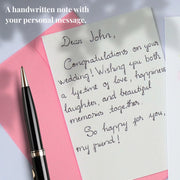 Example of a personal message handwritten on a card insert beside a pink envelope and pen