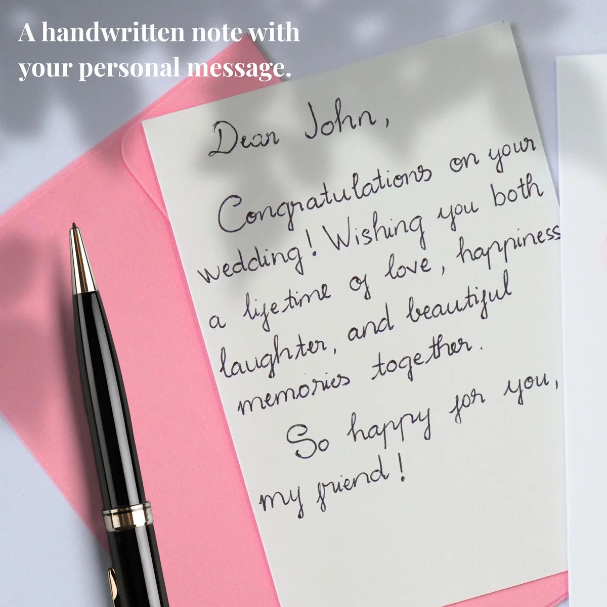 Example of a personal message handwritten on a card insert beside a pink envelope and pen